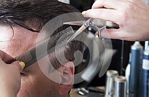 Barber cuts hair of handsome satisfied client.