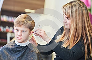 Barber or hair stylist at work. female hairdresser cutting child hair