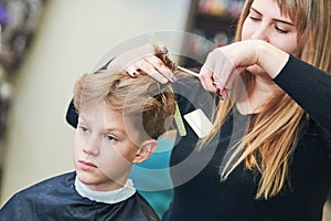 Barber or hair stylist at work. female hairdresser cutting child hair