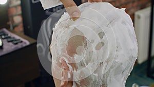 Barber hand shaving bald man with straight razor in male salon. Close up shaving head by straight razor and foam in