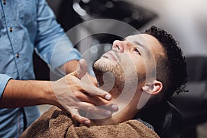 Barber, hands and facial maintenance in barbershop with blade, person and salon. Professional hairdresser, beard and
