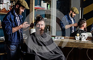 Barber and hipster client with beard checking haircut in mirror, dark background. Man with beard explain hairstyle he