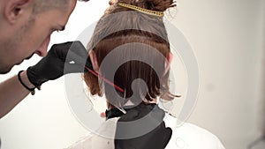 Barber holding a comb and scissor perfoming a haircut for a ginger client