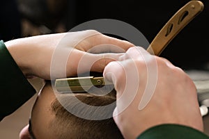 The barber makes the outline with a dangerous razor the undercut haircut