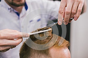 Barber Making Haircut Bearded Man In Barbershop. Professional stylist cutting client hair in salon. Barber using