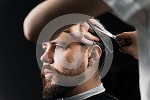 Barber making hairstyle for confident bearded hipster. Advertising for barbershop and men& x27;s beauty salon.