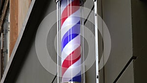 Barber pole rotating on old wall of hairdresser shop