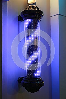 Barber pole turning swirl LED light sign in dark background