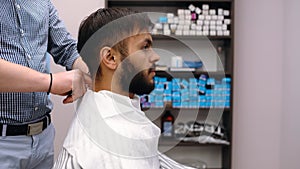 Barber prepares the client for a haircut, ties a napkin. Modern small business concept