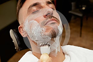 Barber preparing client to shave beard photo