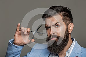 Barber scissors, barber shop. Brutal man, moustache. Portrait of stylish professional hairdresser with beard. Man