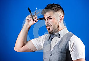 Barber secrets. Barber holding vintage barber tools. Bearded man with razor and scissors in retro barbershop. Hipster