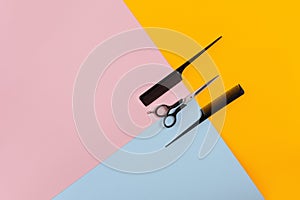 Barber set with two combs and scissors on the color pink, yellow, blue paper background