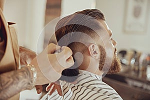 Barber shakes hair off from the client`s neck