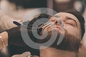 Barber shaves a man`s beard