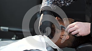 Barber shaving his client with classical razor