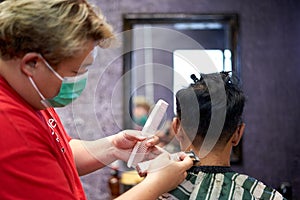 Barber shaving the nape of a client using a clipper and comb