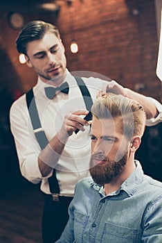 Barber shop classy dressed handsome stylist is doing a perfect h