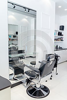 Barber shop in a light style without people, black leather chair for hairstyles, barber chair indoors, barbeshop