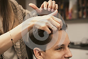 Barber shop men hairstyle. Young man getting a modern haircut. Hair salon master does hair styling client at barber