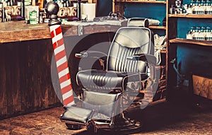 Barber shop pole. Logo of the barbershop, symbol. Stylish vintage barber chair. Hairstylist in barbershop interior