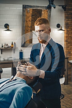 Barber Shop Studios. Barber shaving a bearded man in a barbershop. Beard man visiting hairstylist in barber shop