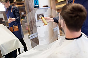 Barber showing hair styling spray to male customer