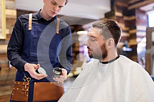 Barber showing hair styling wax to male customer