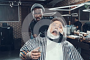 Barber specialist looking at camera holding client head in hand