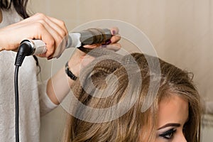 Barber stylist makes a girl hairstyle at beauty salon