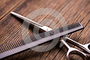 Barber tool on a wooden table surface. Scissors and comb on a vintage background