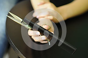 Barber tools in the hands of a professional, long hair, scissors and comb in his hand barber