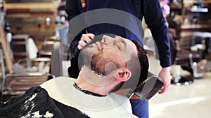 Barber with towel cleaning male face after shaving
