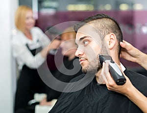 Barber trimming beard with electric razor