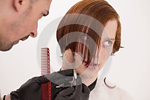 Barber is trimming client`s hair with scissors