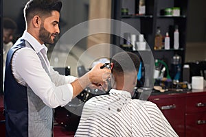 Barber trimming hair of male with clipper in barber shop
