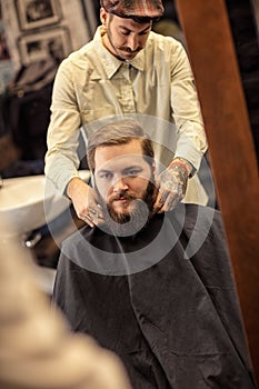 Barber tying apron around customer