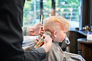 Barber using comb and shaver to cut hair.