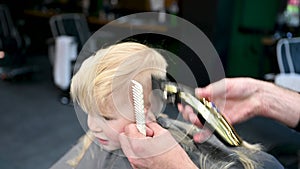 Barber using comb and shaver to cut hair.