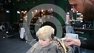 Barber using comb and shaver to cut hair.