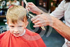Barber using comb and shaver to cut hair.