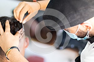 Barber using face mask, doing Highborn and freestyle by hand.