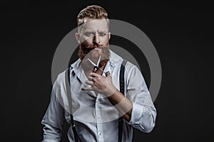 Barber using scissors isolated on black. Haircut from a hairstylist at a barbershop. Bearded Caucasian man hairdresser