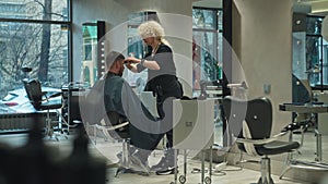 Barber using scissors on man's hair in salon, emphasising beauty and health