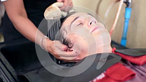 Barber washing hair to young handsome man in male salon. Client in barbershop salon. 1920x1080