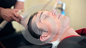 Barber washing hair to young handsome man in male salon. Client in barbershop salon. 1920x1080