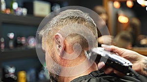 Barber woman cuts bearded man`s hair with a clipper in barbershop. Men`s hairstyling and hair cutting in salon. Grooming