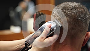 Barber woman cuts bearded man`s hair with a clipper in barbershop. Men`s hairstyling and hair cutting in salon. Grooming