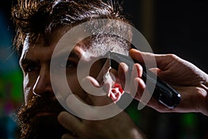 Barber works with hair clipper. Hipster client getting haircut. Hands of barber with hair clipper. Haircut concept