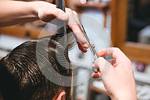 Barbers hands making haircut to man using comb and scissors